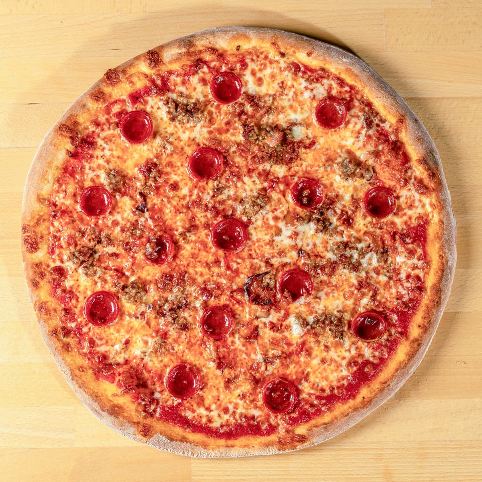 La Pizzeria's pepperoni and sausage pizza, with melted cheese and a golden crust, on a wooden surface.